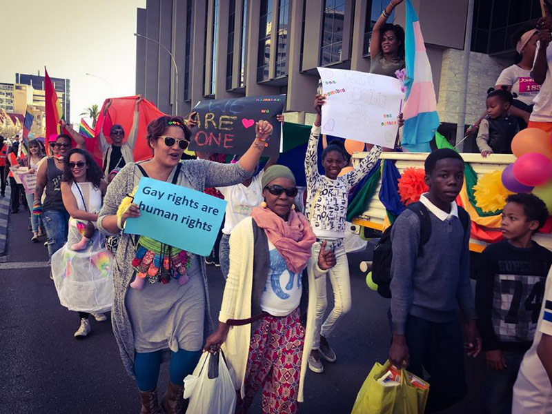 Diverse group of people marching for LGBTQ+ rights. Sign that read "Gay rights are human rights"